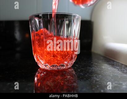 Verre rouge et verser dans le verre en cristal clair Banque D'Images