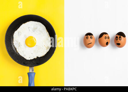 Œuf frit dans la poêle avec les visages tirés sur les œufs non cuits à la télévision, inquiets jeter droit Banque D'Images