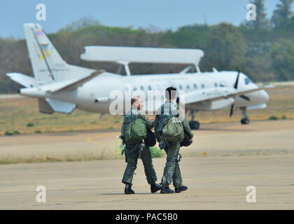 Deux pilotes de l'armée de l'air de la République de Singapour marchent et observent un avion SAAB 340 AEW de la Royal Thai Air Force passant au cours de l'exercice Cope Tiger 16 à Korat Royal Thai Air Force base, Thaïlande, le 7 mars 2016. Le SAAB 340 AEW est un avion bimoteur à turbopropulseur équipé d'un radar aéroporté d'alerte précoce. Cope Tiger 16 implique plus de 1 200 membres du personnel de trois pays, améliorant ainsi l'interopérabilité, la coordination tactique et la projection de forces combinées dans la région Asie-Pacifique. Banque D'Images