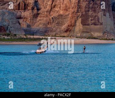 30 mai 2018 - Arizona-Utah, US - un petit bateau remorque une skieur à l'eau passé le géant de falaises sur les rives du lac Powell, réservoir à cheval sur la frontière entre l'Utah et l'Arizona aux États-Unis créé par l'inondation de Glen Canyon par le barrage de Glen Canyon, c'est un endroit de vacances et destination touristique populaire et une partie de la Glen Canyon National Recreation Area administré par le National Park Service. Credit : Arnold Drapkin/ZUMA/Alamy Fil Live News Banque D'Images