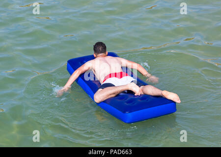 Bournemouth, Dorset, UK. 22 juillet 2018. UK : météo chaude et ensoleillée à Bournemouth plages, comme chef de la mer sunseekers pour prendre le soleil. Man relaxing on matelas gonflable dans la mer. Credit : Carolyn Jenkins/Alamy Live News Banque D'Images