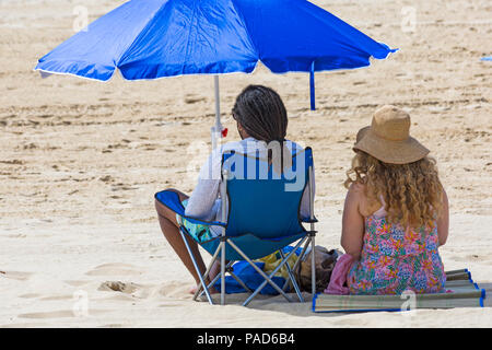 Bournemouth, Dorset, UK. 22 juillet 2018. UK : météo chaude et ensoleillée à Bournemouth plages, comme chef de la mer sunseekers pour prendre le soleil. Couple sitting on beach sous un parasol. Credit : Carolyn Jenkins/Alamy Live News Banque D'Images