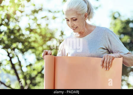 Concentrés senior woman holding un tapis de yoga Banque D'Images