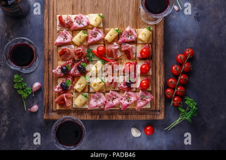 Savoureux savoureux hors-d'Italien tomate, ou bruschetta, tranches de baguette grillées garnie de jambon, jambon sur une planche en bois Banque D'Images