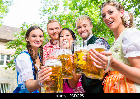 Les amis de s'amuser dans le jardin de la bière alors que clinking glasses Banque D'Images