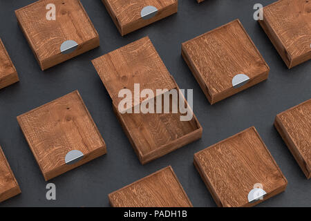 Boîte carrée en bois sombre vide avec couvercle coulissant ouvert avec des boîtes fermées autour sur fond noir. 3d illustration Banque D'Images