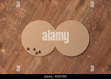 Deux tables rondes du papier craft coasters et les grains de café sur fond de bois. 3d illustration Banque D'Images