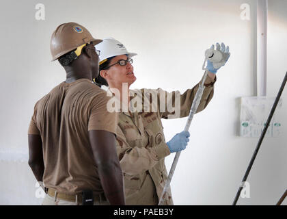 DJIBOUTI (fév. 18, 2011) Le capitaine de la Marine américaine Kathryn Donovan, le Commodore 22e Régiment de construction navale, reçoit une brève leçon en peinture des murs intérieurs de Maître de 3e classe Jemol Gresham, affectés à la construction navale (bataillon Mobile NMCB) 74 Détail Corne de l'Afrique (Det. HOA), à l'Ecole primaire 5 Projet d'école à Djibouti le 18 février 2011. Le capitaine Donovan a visité avec les membres de NMCB 74 et les principaux dirigeants de la Force opérationnelle interarmées combinée de la Corne de l'Afrique (CJTF-HOA) pour assurer l'Seabees sont utilisés de manière efficace dans la fourniture de soutien du génie construction aider CJTF-HOA conformément Banque D'Images