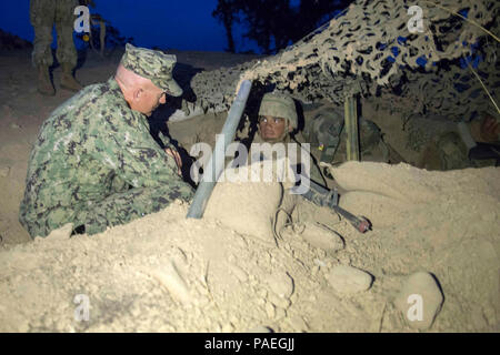 FORT HUNTER LIGGETT (sept. 29, 2015) - Construction navale vigueur (NCG) Commodore 1 Capt Christopher Kurgan parle avec 3e classe métallurgiste Samuel Rojas, affectés à la construction navale (bataillon Mobile NMCB) 4, comme il l'mans un assaut au camp Rovinski position à Fort Hunter Liggett, en Californie, au cours de l'exercice 2015 La formation sur le terrain (FTX), le 29 septembre dernier. La formation est conçue de façon à respecter tous les aspects de la défense du bataillon et les capacités opérationnelles de manning une position de combat sur l'entreprise, afin de réagir aux menaces de guerre chimique et des dispositifs explosifs de circonstance. Banque D'Images