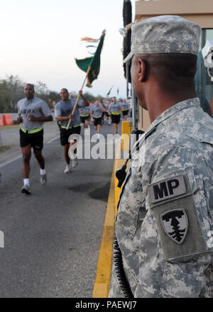 GUANTANAMO BAY, Cuba - Le Sergent de l'armée. Mohammed Ellis monte la garde à la porte de l'armée comme Roosevelt, le Lieutenant-colonel Alex Conyers, 525e Police militaire (PM), chef de bataillon de l'armée et la CPS. Terrence Robinson, exerçant son guidon, le plomb le 525e Bataillon MP dans une formation à la force opérationnelle interarmées (FOI) Guantanamo, le 9 avril 2010. Le 525e Bataillon MP fournit une partie de la force de garde à l'intérieur de la détention à Guantanamo de la foi. Guantanamo la foi mène sûr, humain, juridique et transparent le soin et la garde des détenus, y compris ceux qui ont été condamnés par une commission militaire et ceux commandés libéré par un tribunal. T Banque D'Images