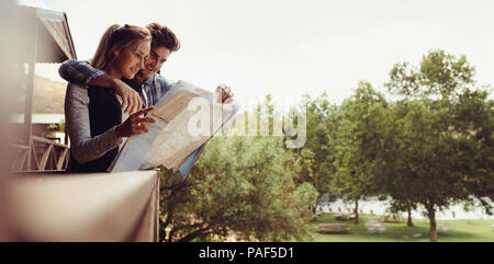 Couple à l'extérieur de leur chalet de vacances à la carte à des directions. L'homme et la femme en vacances à la position sur une carte. Banque D'Images