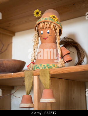 Marionnette faite de pots et de paille assis sur un conseil, yeux bleus, cheveux en paille Banque D'Images