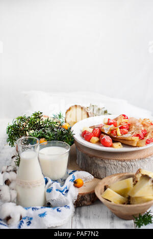 Sucré fait maison crêpes minces pour le petit-déjeuner avec des fruits et des baies. Dans un verre de lait et d'ananas. Sur un fond blanc. Espace libre pour le texte Banque D'Images