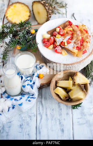 Sucré fait maison crêpes minces pour le petit-déjeuner avec des fruits et des baies. Dans un verre de lait et d'ananas. Sur un fond blanc. Espace libre pour le texte Banque D'Images