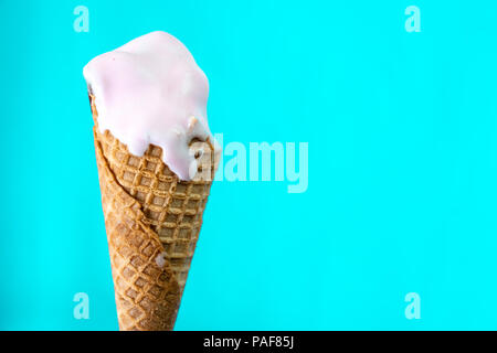 Cornet de crème glacée fondue sur fond bleu menthe Banque D'Images