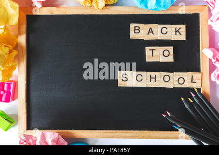 Mise à plat du tableau noir avec cadre en bois avec texte retour à l'école, les crayons de couleur, papier et émietté balls Banque D'Images