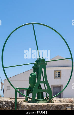 Pompe pour le vert de l'eau d'un puits. Square dans une petite ville historique portugaise. Maison avec façade blanche. Ciel bleu. Cacela Velha, le Portugal. Banque D'Images