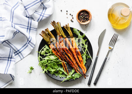 Carottes rôties et salade végétarienne vert frais. Vue d'en haut. Salade végétalienne saine sur la plaque noire Banque D'Images