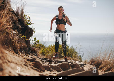 Toute la longueur de course femme fitness plus rock trail sur la montagne. Fit young woman running jusqu'à une colline. Banque D'Images