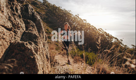 Femme en marche sur terrain extrême sur la colline. La formation à l'extérieur coureuse sur rocky mountain trail. Banque D'Images