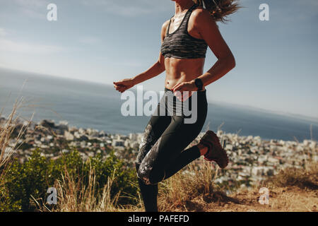 Sprint femme en bonne santé plus de sentier de montagne. Femme faisant courir entraînement sur chemin sur la colline parlementaire. Cropped shot. Banque D'Images