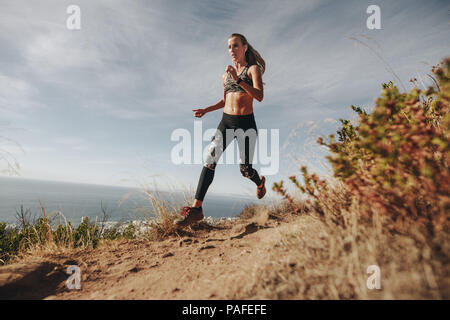 Fit sports femme sprint sur sentier rocheux sur la montagne. Woman running descente sur sentier de montagne. Banque D'Images