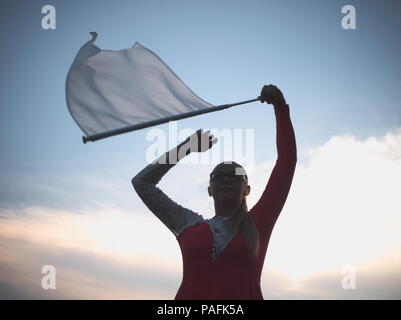 Teen blonde à lunettes fille Majorette avec drapeau blanc à l'extérieur en robe rouge Banque D'Images