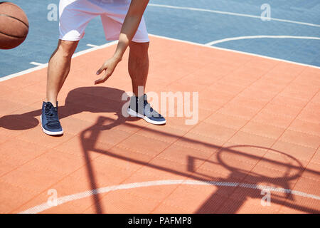 Les jeunes adultes asiatiques jouant au basket-ball sous soleil de l'été sur une cour. Banque D'Images