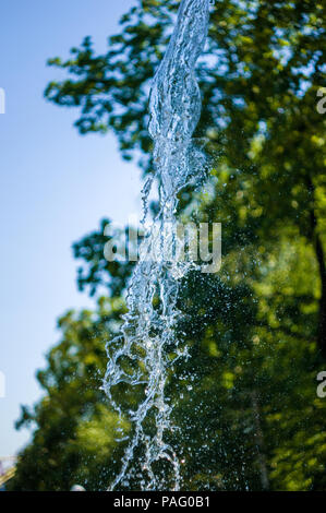 La chute de l'eau transparent flux vertical contre un ciel bleu et vert paysage, close-up Banque D'Images