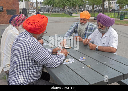 Cinq hommes sikhs jouant le jeu de carte s'infiltrer en plein air à Smokey Park à Richmond Hill, Queens New York City. Banque D'Images