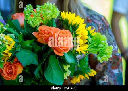 Jeune femme tenant un bouquet de fleurs asymétriques modernes sur l'un tournesol en face du champ Banque D'Images