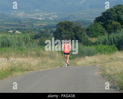 Coureuse unique bénéficiant d'un matin tôt courir à travers les ruelles autour de Magalas, France Banque D'Images