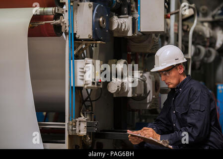 Factory worker writing on clipboard in factory Banque D'Images