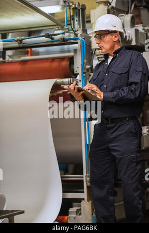 Factory worker writing on clipboard in factory Banque D'Images