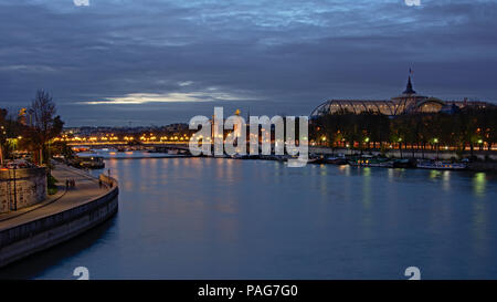 L'exposition longue vue de nuit sur le Pont Alexandre III pont sur Seine, et le toit de verre et d'acier du Grand Palais au-dessus des arbres le long du quai en Banque D'Images