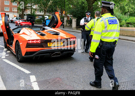 Sloane Street, Londres, Royaume-Uni, le 20 juillet 2018. Arrêt de la police, puis parler à la propriétaire de cette colère Lamborghini orange, tandis que la foule se développe autour de la voiture. Supercars, haute performance et des voitures classiques, ainsi que quelques adaptations de caractère, s'alignent et conduire le long de Sloane Street pour Supercar Dimanche, qui voit autour de 400 voitures présentes. Banque D'Images