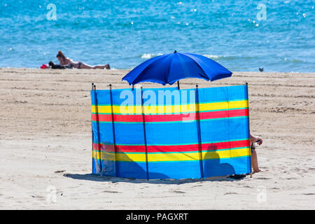 Bournemouth, Dorset, UK. 23 juillet 2018. Météo France : la canicule se poursuit à la hausse des températures sur une brulante et journée ensoleillée à plages de Bournemouth avec ciel bleu et soleil ininterrompue. La station de tête Sunseekers pour prendre le soleil. Brise-vent de soleil derrière sous un parasol. Credit : Carolyn Jenkins/Alamy Live News Banque D'Images