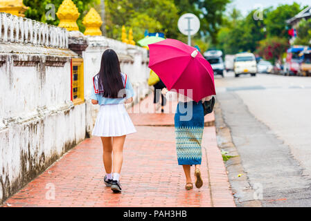 Les gens sur une rue de ville sous un parapluie dans Louangphabang, Laos. L'espace de copie pour le texte Banque D'Images