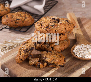 Pile de cookies à l'avoine et aux raisins avec des flocons d'avoine dans une cuillère sur une planche en bois Banque D'Images