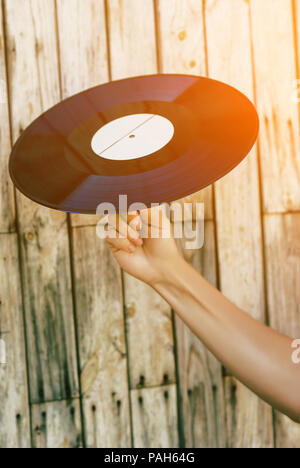 Femme hand holding vinyl record sur fond de bois Banque D'Images