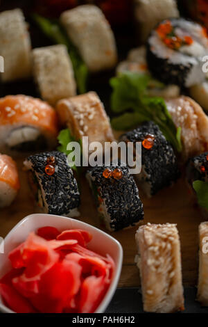 Set à Sushi photo alimentaire. Servi sur des rouleaux en bois marron et plaque en ardoise. Close up of sushi. Banque D'Images