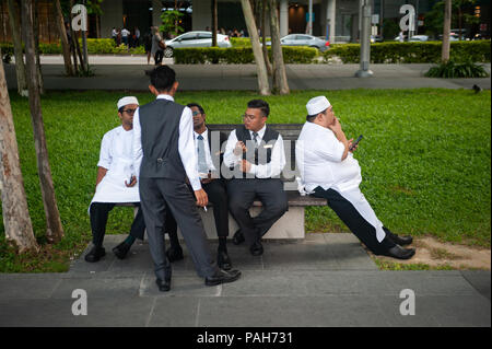 13.07.2018, Singapour, République de Singapour, en Asie - un groupe d'employés d'hôtel est vu prendre une courte pause sur un banc à Marina Bay. Banque D'Images