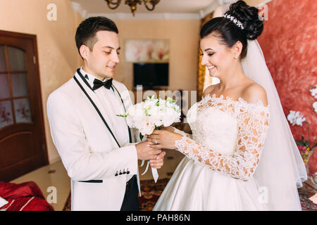 Vue rapprochée de l'heureux marié donnant le mariage bouquet de la mariée en souriant. Banque D'Images