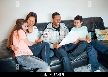 La famille sont de détente sur le canapé tandis qu'ils donnent son père Father's Day gifts. Banque D'Images