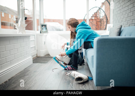 Petite fille est mise sur des patins dans la véranda de sa maison avant qu'elle va à sa leçon de patinage. Banque D'Images