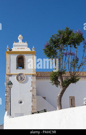 Tour de Igreja Matriz de Alvor - église dans une ville portugaise. La façade blanche avec des détails jaunes. À côté de l'arbre de l'immeuble. Ciel bleu. Alvor, Alg Banque D'Images