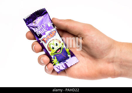 Un garçon tenant une barre de chocolat Cadbury Freddo sur un fond blanc. Banque D'Images