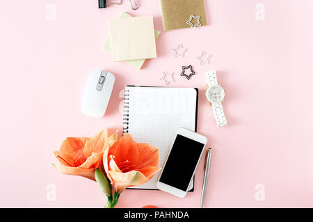 Mise à plat, vue du dessus table office 24. Espace de bureau féminin avec fleur amaryllis, bloc-notes, stylo, smartphone, souris d'ordinateur et les femmes sur rose retour Banque D'Images