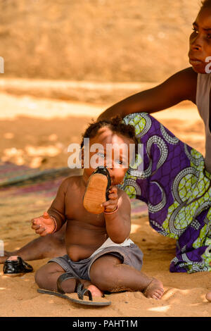 Lomé, Togo - Mar 9, 2013 Le Réseau non identifié : cute little baby girl met une chaussure dans la bouche. Peuple Togolais souffrent de la pauvreté en raison de l'instabilité de l'éco Banque D'Images