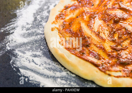 La préparation de pizza, close-up de la pâte à pizza avec la sauce tomate. Banque D'Images